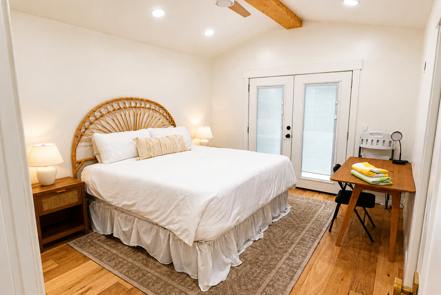 Primary bedroom with cane headboard and French doors
